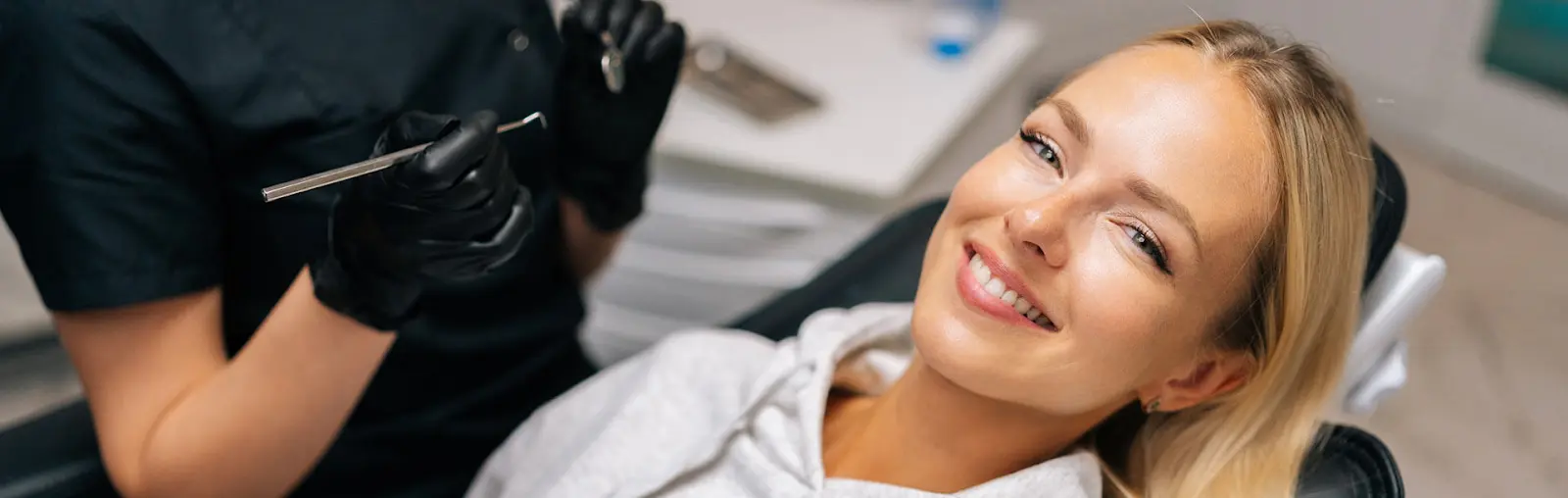 Woman smiling in dental chair with dentist holding tools