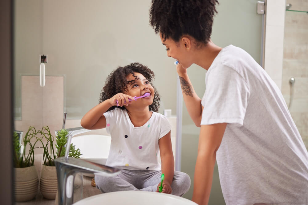 Mother and daughter brushing their teeth together i