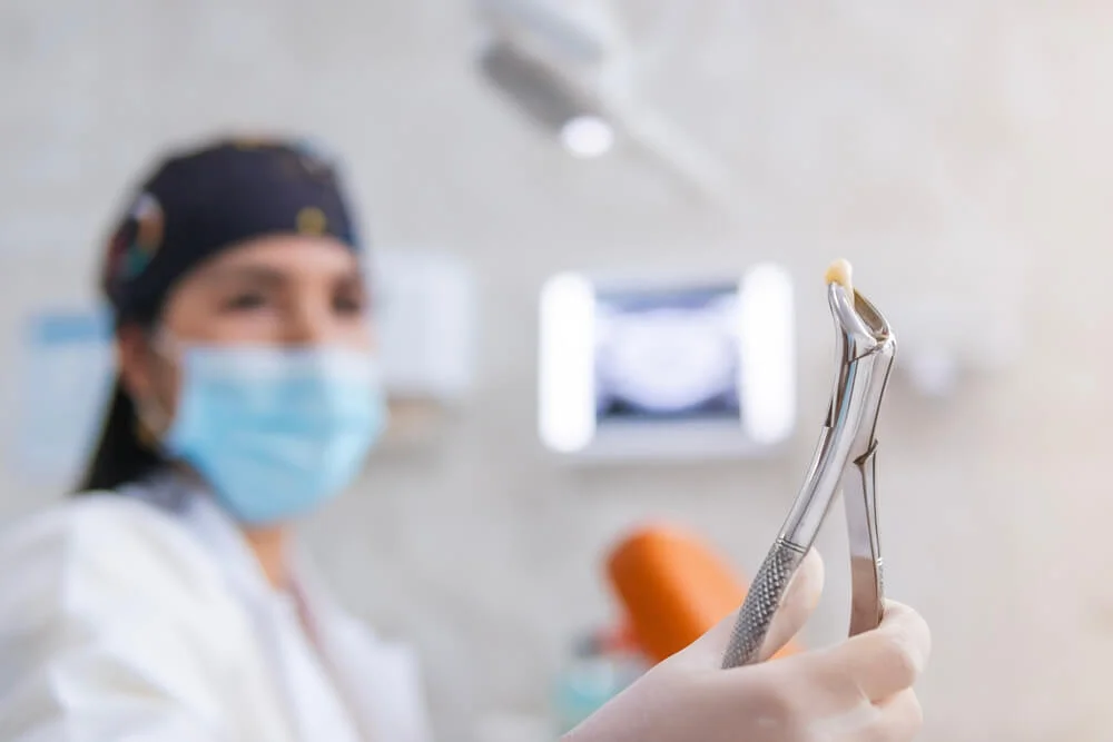 Dentist holding extracted tooth with forceps