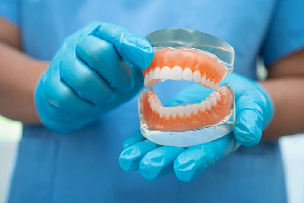 Dental professional holding a model of full dentures
